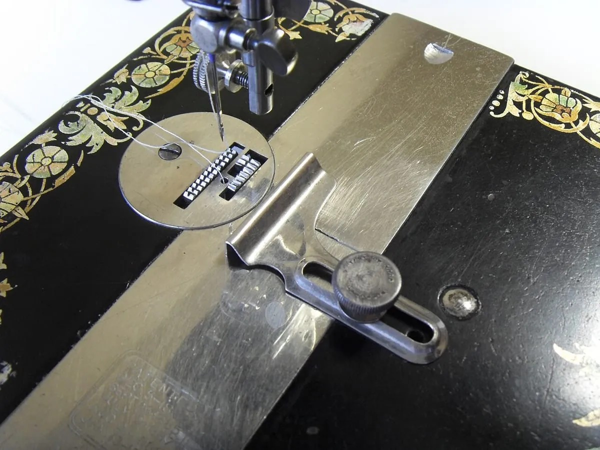 Hands guiding fabric under the needle of an industrial sewing machine. No faces.