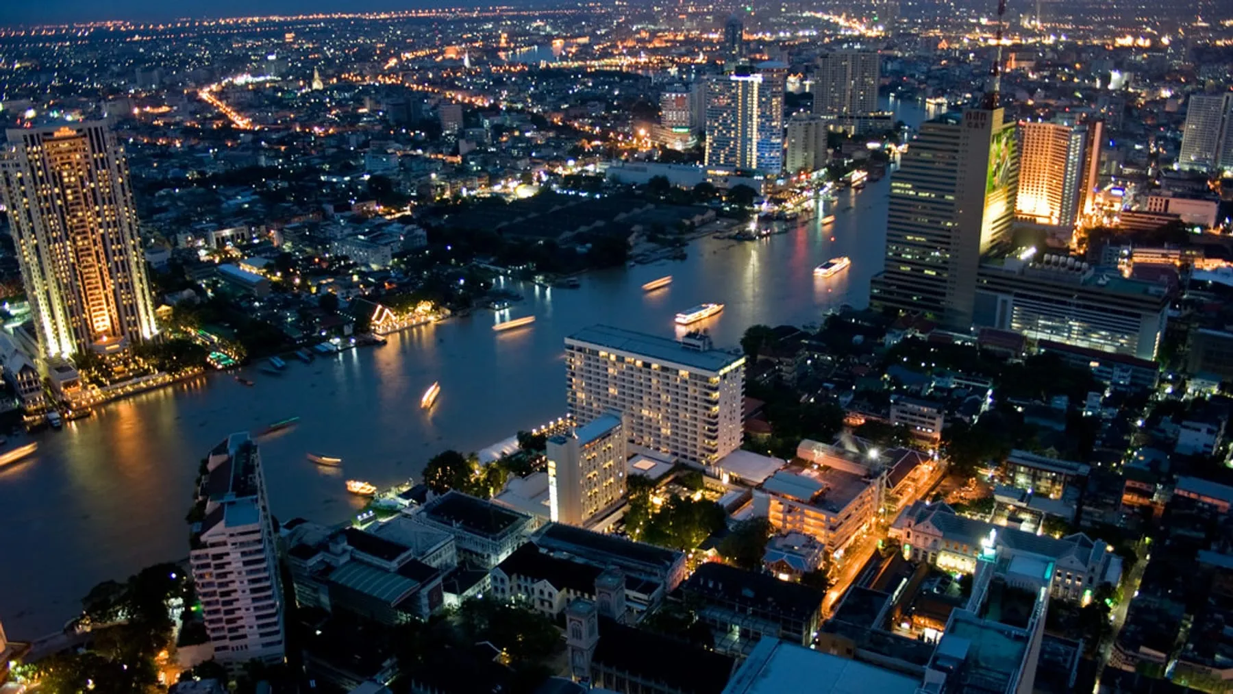 Bangkok at dusk from above, traffic lights beginning to come on, the sky still light.